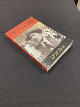 Paperback book with a maroon coloured spine that shows the title printed in black and the author's name printed in gold. The front cover shows a large image of Nurse Wilma Oram Young in uniform when she was a young lady with hat and tie, in the background to the left is an image of Wilma in full nurses attire and to the right is an image of her as an older lady wearing medals and being supported by a soldier in uniform. There is a black strip along the bottom of the front cover with the author's name printed in gold. Along the top of the cover is a maroon strip with the title and subtitled printed.