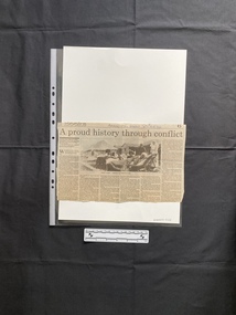 A large newspaper clipping of a title, six columns of text and a black and white photo