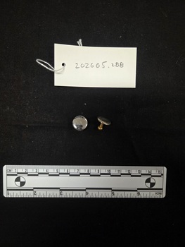 Two aluminium and brass cufflinks. The front face of the cufflinks is aluminium and the shank is brass.
