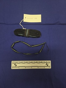 Two pieces of airforce ribbon. The ribbon is comprised of black ribbing with a central line of cross-grain pale-blue ribbing. One long piece rolled into a loop and secured with a pin.  One short, narrow piece with frayed ends.