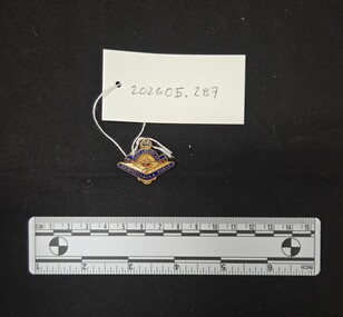Metal and enamel badge featuring a variant of the tri services symbol including a rising sun, anchor and a pair of wings. A blue enamel semicircle of scroll work is above this with the text 'AUST. LEGION OF' with a crown shape above it and the numbers '46' in metal against blue enamel. Below the wings is a boomerang shape in blue enamel with the text 'EX-SERVICEMEN & WOMEN'. 