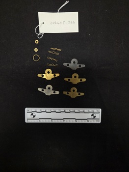 Various attachment parts for airforce epaulettes, including five metal backing plates, five metal split pins, hexagonal brass nut, and metal jump ring.
