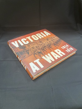 Hardcover book with dust jacket. Title printed in large, bold, white text along spine and across the top and bottom of the cover. In the background is an image of rows of soldiers marching down a town street. The cover is a burnt orange colour.