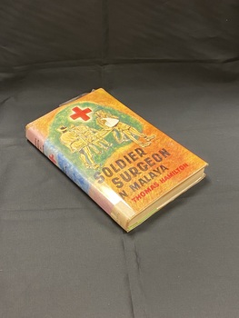 Green hard-cover with dust-jacket.The cover is orange and green with a red medical cross at the top and a drawing of wounded soldiers being assisted by medics, the title is below in black and the author's name in red. The cover image wraps around onto the spine.