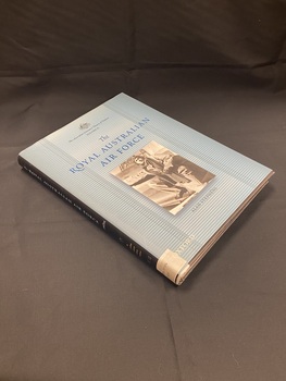 Black hardcover with blue dust-jacket and black spine. Title, author and series title printed along spine, as well as a white label taped to the base with the DDC number typed across it. The front cover is light blue with darker lines running horizontally across. The title is printed in darker blue with a black and white rectangle image of an air force serviceman against a plane, in the centre of the page.