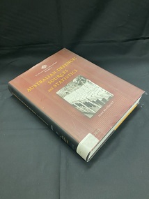 Dust-jacket has a black spine and back cover. There is a white spine label taped across the bottom of the spine. The front cover is burgundy with faint stripes and a black and white image of a row of white crosses in the centre. The title appears in orange print above the image. Author's name and series title also appear on the front cover in white text.