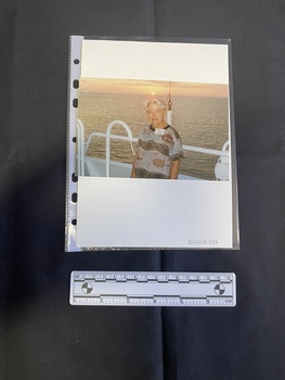 Colour photo portrait of an older woman standing in front of a railing with a large body of water in the background.