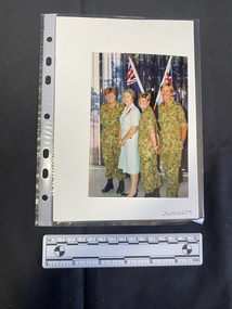 Colour photo of four women in uniform standing in front of two flags.
