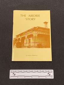 Thin paperback with two staples down the spine. Yellow cover with a sepia image of Airdrie House on the front and the title and author printed in brown.