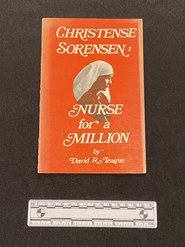 Thin red paperback with two staples in the spine. The title is written in large white print on the cover and in the middle is a portrait image of Christense.