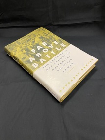 Hard-cover book with cream coloured dust jacket. There is an olive green and black toned photographic image wrapped around the top half of the cover and spine, it shows soldiers leading a man with bandaged eyes towards a jeep in the jungle, with other soldiers gathered around.
The lower half of the cover is cream with blue text. There is a white label on the base of the spine with blue handwritten call number .
