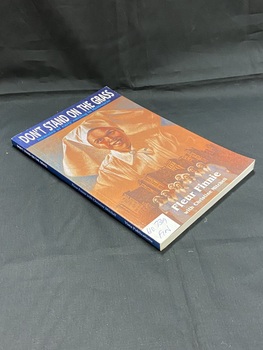 Blue paperback book with the title printed in white across the top of the front cover and along spine. The remainder of the cover is covered by a blue and brown illustration of a nurse in white uniform, overlaid along the bottom is a drawing of 8 nurses in blue and white uniforms standing in front of a row of buildings. There is a white spine label sticker in the bottom left corner of the front cover.