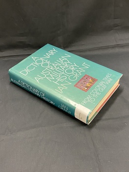 Hardcover book with a dark green dust jacket. Title is printed in white across the cover and spine. There is a small framed illustration of three military men on the lower part of the cover. There is a white spine label sticker at the base of the spine.