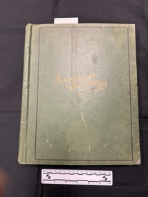 Green album/scrapbook closed.  Front cover and spine show wear, water marks and fading.