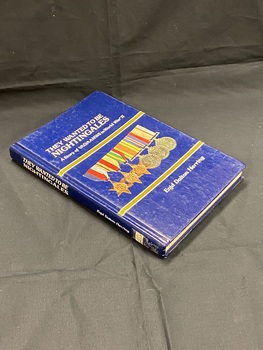 Blue hardback book. Title printed down the spine. Cover has two gold lines across the front, above the top line is the title in white; below the bottom line is the author's name, between the two lines in the middle are a row of six military ribbons and medals.