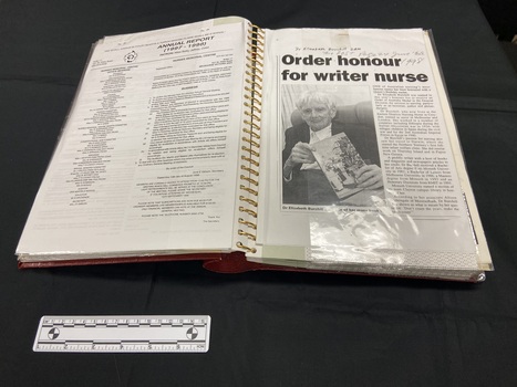 An example of the inside page layout displaying two open pages and the spiral binding in the centre. One side has a printed and typed annual report and the right side has a copy of a newspaper clipping.
