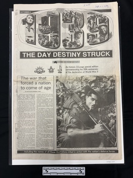 A large black and white newspaper lift-out with the cover showing the numerals 1939 filled with photos collaged together, several large headlines and subtitles, one article with two columns and a large captioned photo of a man in uniform with a gun on his shoulder, cigarette in his mouth, wearing a hat.
