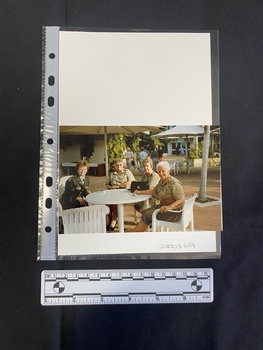 A colour photograph of four women in military uniform sitting at an outdoor table