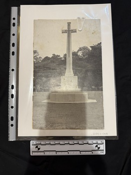 Black and white booklet containing photographs and text.  Cover image is of a large stone cross atop a multi-tiered base, with an embossed sword shaped cross on its face.  The memorial is on a lawn with shrubs and dense trees in the background.  It is known as the Cross of Sacrifice.  Inside the booklet there is an accompanying letter.