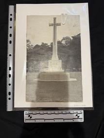 Black and white booklet containing photographs and text.  Cover image is of a large stone cross atop a multi-tiered base, with an embossed sword shaped cross on its face.  The memorial is on a lawn with shrubs and dense trees in the background.  It is known as the Cross of Sacrifice.  Inside the booklet there is an accompanying letter.