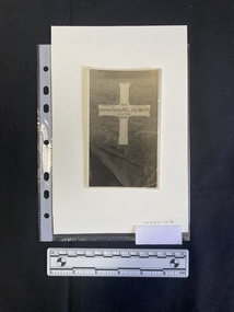 A black and white photo of a headstone in the shape of a cross