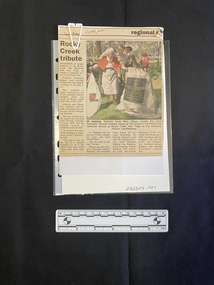 Folded A5 booklet printed on white paper, consisting of pictures and text. Text outlines the order of ceremony.  Newspaper clipping consists of a title, caption, four columns of text and a colour photo.
