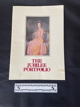 Paperback booklet with white gloss cover showing a portrait of the Queen with a silver border and the title printed in deep red below.