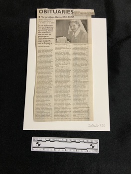 Newspaper clipping with heading typed in bold at the top and three columns of text. At the top of the first column is one paragraph in bold type. At the top of the other two columns is a photo of a woman holding a document, wearing a nurses uniform.