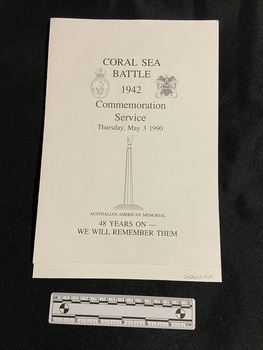 Single-fold white card. Service details printed on front cover in black print with the emblems of the Royal Australian Navy and the United States Marines on either side. There is an image of a memorial statue beneath the service date.