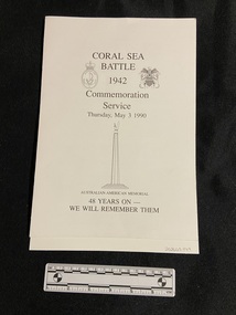 Single-fold white card. Service details printed on front cover in black print with the emblems of the Royal Australian Navy and the United States Marines on either side. There is an image of a memorial statue beneath the service date.