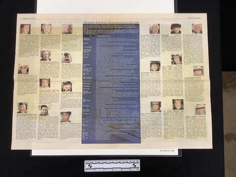 Centre newspaper spread with twenty colour headshot captioned photographs and a large central box with text as a chronology and blue background.  Spread has a red border at the top of the page underneath publication information.