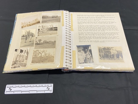 Inside layout shows seven black and white 2.7x3.7 photographs under protective plastic sheet on the left. The right side has a typed document with two photographs placed at the bottom, also under the protective plastic. The protective pages are held down by tape.