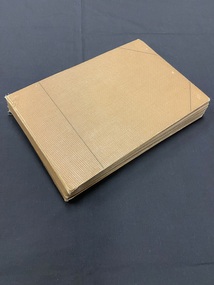 Brown hardback album with a thin dark line running vertically down the front cover an inch in from the spine and a diagonal line across the two corners of the cover on the right side.