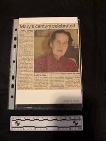 A newspaper clipping with a colour photograph of an elderly woman.  Beneath the photo are four columns of text.