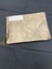 Worn brown photograph album bound with thread and tied in a bow on the left hand side. White sticker label in the top left corner covering an image of the sun, it's rays spread out across the rest of the cover. Printed diagonally in the bottom right corner are the words 'happy snaps'.