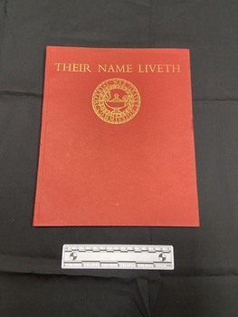 Red paperback book with thin spine. Front cover has the title printed across the top in gold, beneath is a circular emblem of the Imperial War Graves Commission.