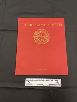 Red paperback book with thin spine. Front cover has the title printed across the top in gold, beneath is a circular emblem of the Imperial War Graves Commission.