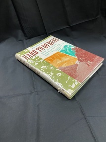 Green hard cover book with dust jacket that has plastic covering. White spine with title printed in brown print and author in green, spine label at the base starting to peel off. Front cover has a strip down the left side with images of many faces in green. Title is printed across the top in brown with subtitle in green. Lower right side has a a collage of three images overlapping, a man and dog in an orchard, a man ploughing a field with many horses, and a newspaper clipping.
