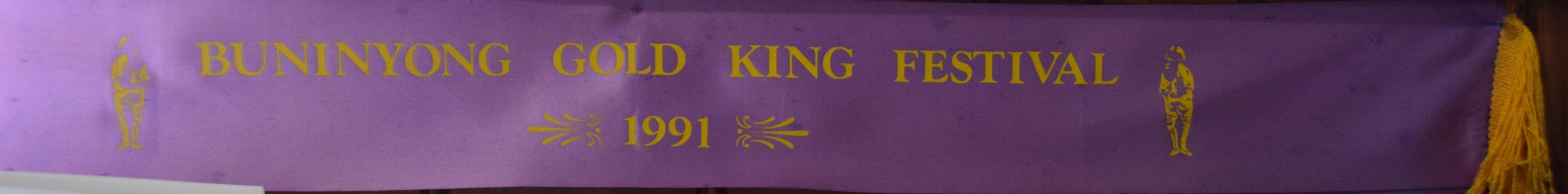 Purple sash with printed gold writing used in the 1991 Buninyong Gold King Festival.
