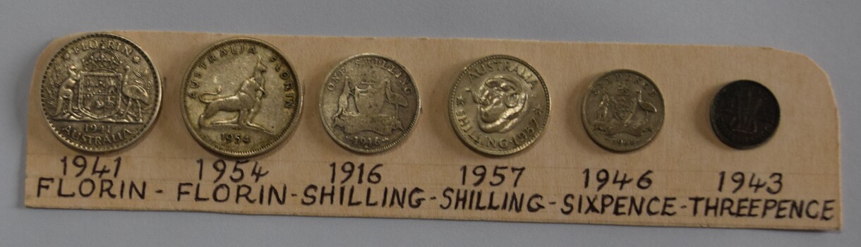 Seven pre-decimal coins fixed wo a labelled card. 
