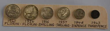 Seven pre-decimal coins fixed wo a labelled card. 