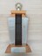 Two wooden pillars with black grille between, gold wreath and plates on pillars and base