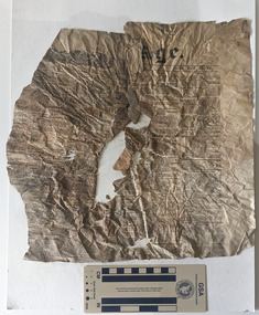 Damaged fragment of a newspaper with a rip along the centre of the page.