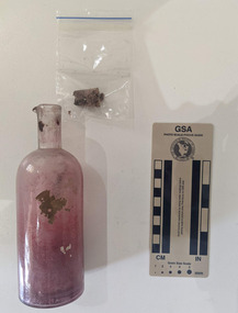 Small pink glass bottle with a cork and fragments of paper inside 