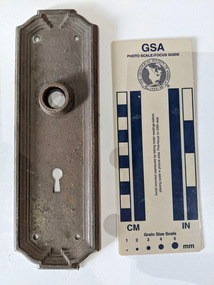 Historic door plate with an embossed boarder and key hole.