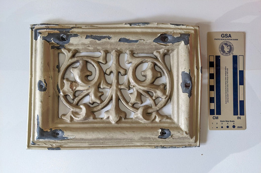Cream painted lead ventilation grate with geometric design.