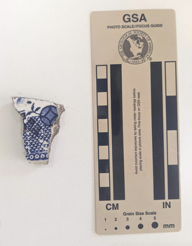 Ceramic shard with white glazed finish and a blue geometric design.