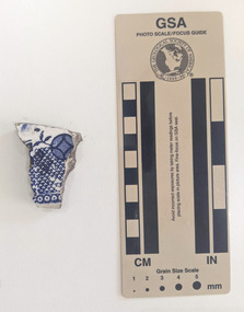 Ceramic shard with white glazed finish and a blue geometric design.