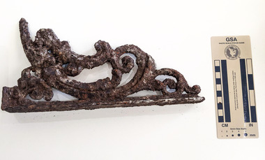 A decorative architectural element made of iron that is badly corroded     