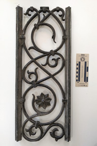 Iron architectural grate with a spiral design with a flower at the centre. 